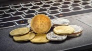 Image of pile of cryptocurrency including Bitcoin on a laptop.